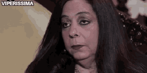 a woman with long black hair is sitting in a chair looking at the camera .