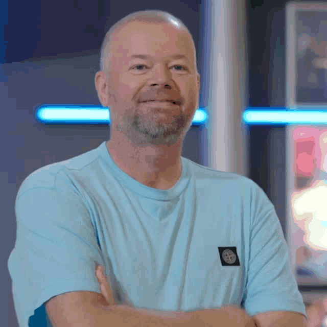 a man wearing a light blue t-shirt with a stone island patch