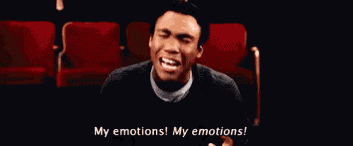 a man is sitting in a theater with his eyes closed and making a face .