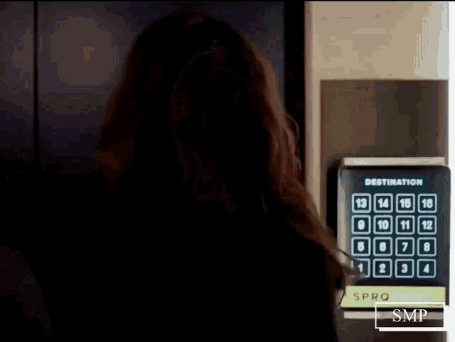 a woman is standing in front of a keypad with numbers on it .