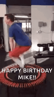 a man is jumping on a trampoline with the words `` happy birthday mike '' written on it .