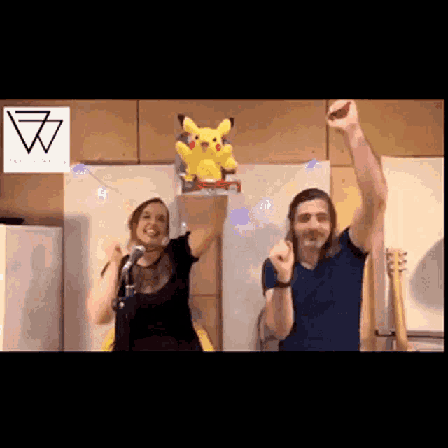 a man and a woman are dancing in front of a pikachu toy