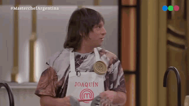 a man wearing a white apron with the name joaquin on it