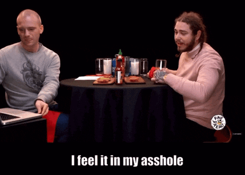 a man with a beard wearing a pink shirt that says i feel it in my asshole on it