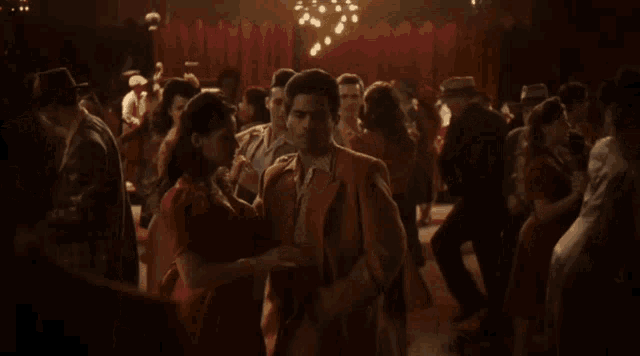 a group of people are dancing in a room with a red curtain behind them