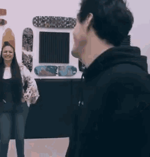 a man and woman are standing in front of a wall with skateboards on it .