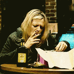a woman sitting at a table with a bottle of beer