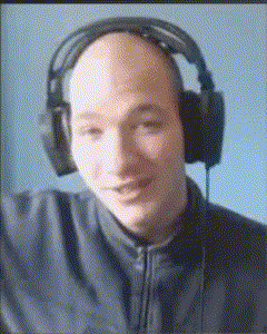 a bald man wearing headphones looks at the camera and smiles