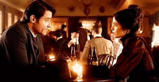 a man and woman are sitting at a table looking at each other in a restaurant .
