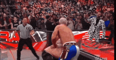 a referee is standing between two wrestlers in a ring during a wrestling match .