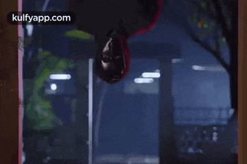 a man in a superhero costume is hanging upside down from a window .
