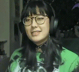 a woman wearing glasses and headphones is smiling and wearing a green shirt .
