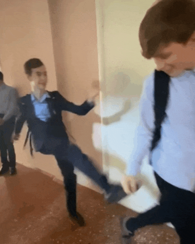 a boy in a suit is kicking another boy in the face