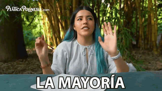 a woman with blue hair is sitting at a table with the words la mayoria written on the table