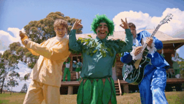a man in a green wig is holding a guitar that says fender on it