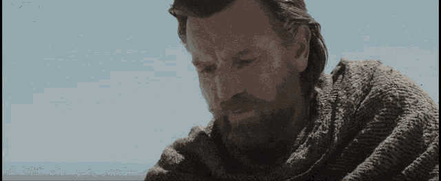 a man with a beard and long hair is wearing a grey sweater