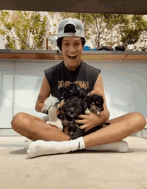 a man wearing a black tank top that says ' iron maiden ' on it is holding a bunch of puppies