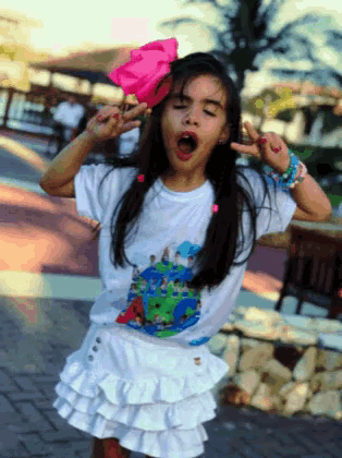 a little girl with a pink flower in her hair is making a face