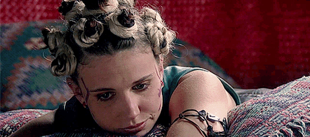 a woman with curlers in her hair is laying on a bed with a bracelet on her wrist .