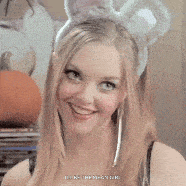 a woman wearing a bunny headband is smiling and says ill be the mean girl
