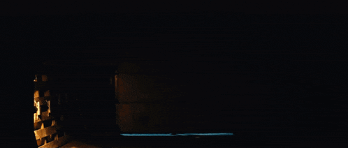 a man in a black jacket is walking through a dark alleyway