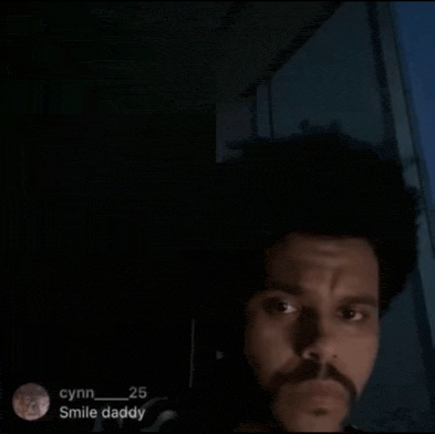 a man with a beard is looking at the camera in the dark .