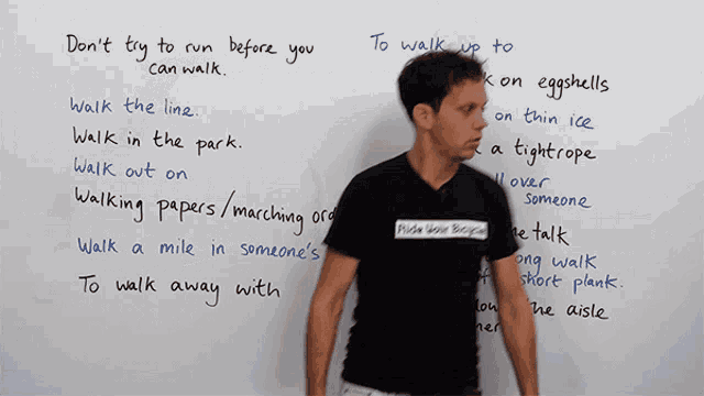 a man in a black shirt stands in front of a white board that says " don t try to run before you can walk "