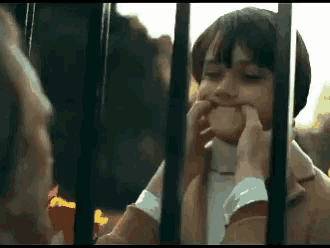 a little girl is making a face behind bars