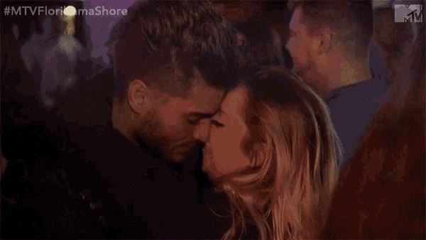a man and woman are kissing in front of a crowd .
