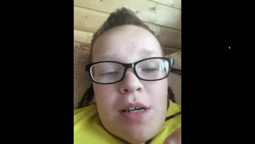 a person wearing glasses and a yellow shirt is laying down