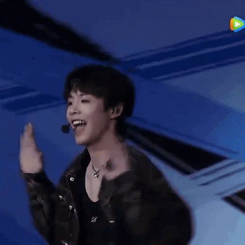 a young man is dancing on a stage with a microphone .