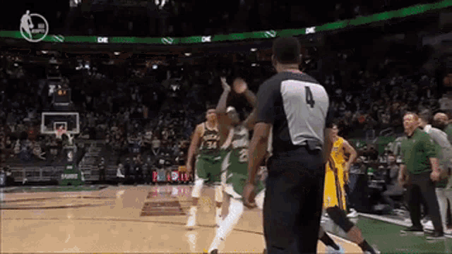 a referee with the number 4 on his back stands in front of a basketball player