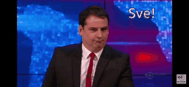 a man in a suit and tie with the word sve on the screen behind him