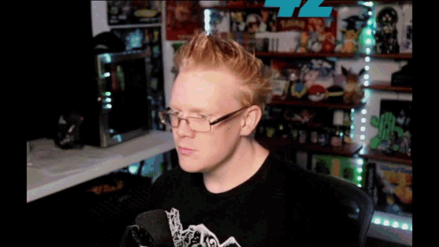 a man wearing glasses is sitting in front of a microphone in a room
