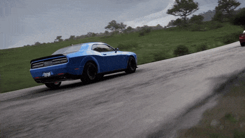 a blue dodge challenger is driving down a road next to a red car