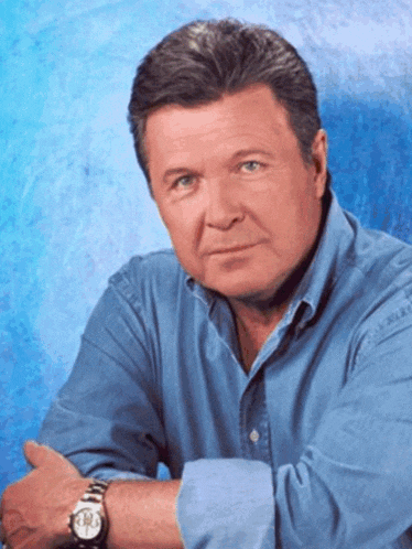 a man in a blue shirt has a watch on his left wrist