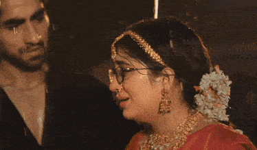 a woman wearing glasses and a nose ring stands next to a man