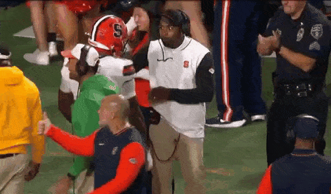 a football player wearing a helmet with the letter s on it is walking on the field .