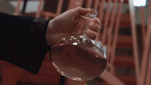 a person is holding a clear glass bottle