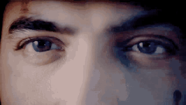 a close up of a man 's eyes with a blood spot on his forehead