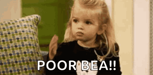 a little girl is sitting on a couch with a pillow and a sign that says poor bea .