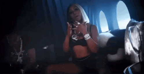 a woman in a crop top is sitting on a plane with a man behind her .