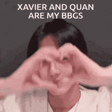 a man is making a heart shape with his hands in front of his face