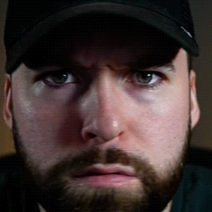 a close up of a man 's face with a beard wearing a black hat