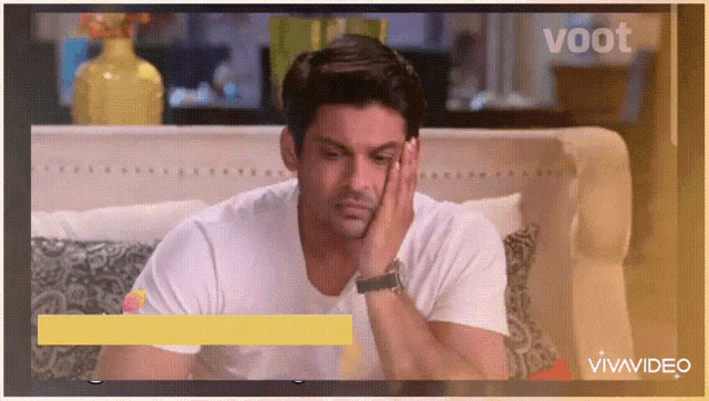 a man is sitting on a couch with his hand on his face and the word voot is on the screen