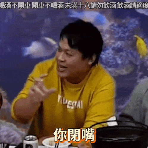 a man wearing a yellow shirt that says illegal is sitting at a table