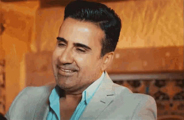 a man in a suit and blue shirt is smiling .