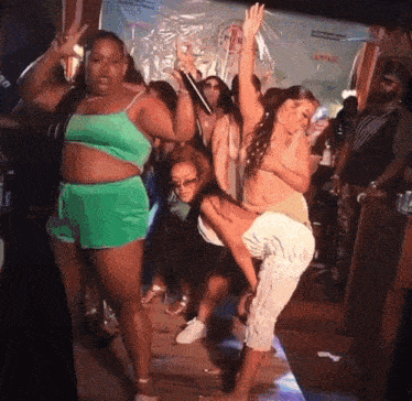 a group of women are dancing in a room with a sign that says campari