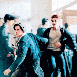 a man in a denim jacket is running with another man in a black jacket