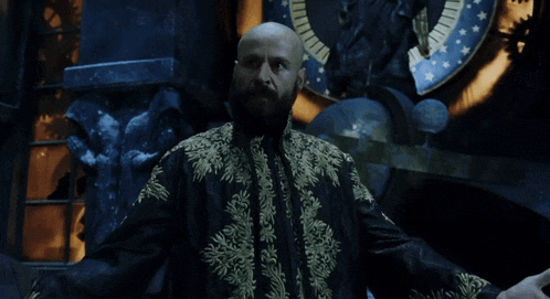 a bald man with a beard wearing a black and gold coat